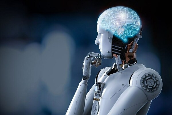 An android robot rests its chin on its hand in a thinking pose. A pattern of circuits in the shape of a brain is projected on the android's "head"